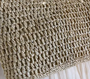 Gros plan sur la texture tissée main en paille et la fibre naturelle de ce sac de plage