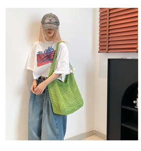 Detalle de bolso bandolera tejido calado verde claro con colgante floral en una modelo