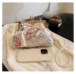 Detail of embroidered flower fan pattern on traditional shell-shaped handbag with pearls