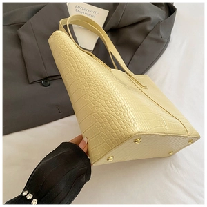 Détail du sac cabas crème gaufré crocodile montrant les pieds en métal et la base solide