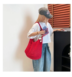 Detalle del bolso hobo de ganchillo rojo con colgante de tulipa y textura tejida de playa
