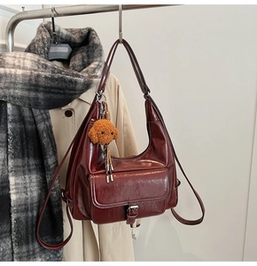 Detail of dark red oil wax leather crossbody bag with a cute teddy bear charm