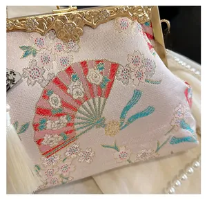 Detail of pink satin shell bag featuring cherry blossom embroidery and golden metal frame