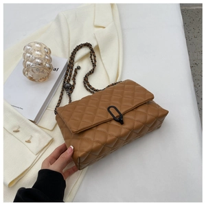 Detail of caramel brown quilted leather bag with woven chain strap and metal ball