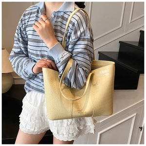 Détail d'un sac cabas jaune clair à motif crocodile porté par un mannequin