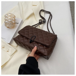 Close-up of quilted dark brown flap bag with unique black metal clasp and chain strap