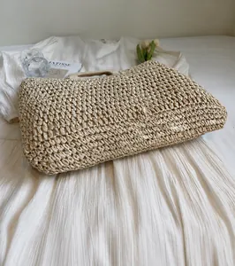Détail d'un sac de plage en paille tressée à la main avec poignées en bois semi-circulaires