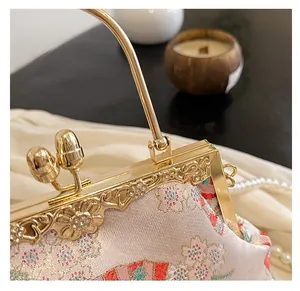 Close-up of golden metal frame with floral embroidery and rhinestone details on shell bag