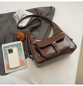 Detailed view of dark brown gloss leather bag with front flap pocket and bear charm
