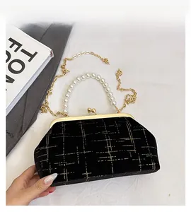 Détail du sac en velours noir avec motif grillagé doré, poignée perle et chaîne en métal