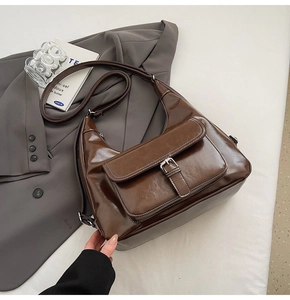 Detail of dark brown oil wax leather hobo bag with contrast stitching and silver buckle