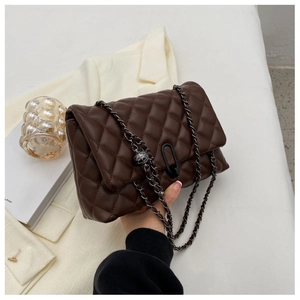 Detail of dark brown quilted leather handbag with metallic horseshoe lock and chain strap
