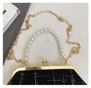 Détail du sac coquillage en velours noir avec matelassage doré et anse en perles