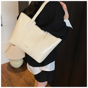 Sac fourre-tout blanc crème à texture crocodile porté à l'épaule par un mannequin de mode