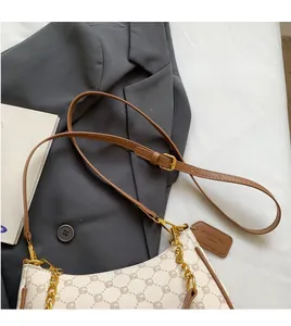 Close-up of beige plaid crossbody bag featuring metal chain and adjustable strap