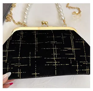 Détail d'un sac coquillage en velours avec lignes dorées et chaîne en perles