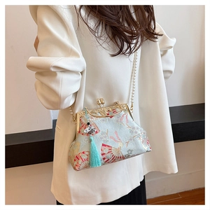 Detail of blue silk chepongs bag featuring floral embroidery, pearl strap and green tassel