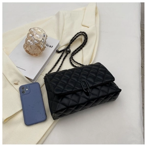 Detail of a black quilted chain bag with a metallic clasp and textured faux leather
