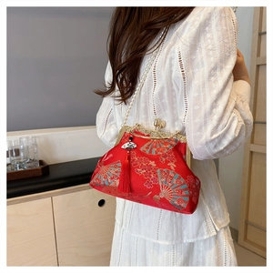 Detail of red oriental shell bag with embroidery, metal handle and pearl strap