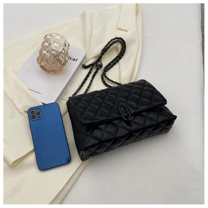 Detail of black quilted leather shoulder bag with U-shaped buckle and metal chain strap