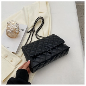 Detail of black quilted leather texture and metallic ring clasp on chain shoulder bag
