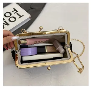 Détail du sac coquillage en velours montrant l'intérieur avec cosmétiques et chaîne