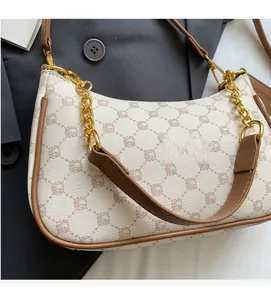 Detail of printed crescent shoulder bag with brown leather trim and golden chain strap