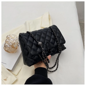 Detail view of black quilted flap bag featuring metal chain and ball slider adjustment