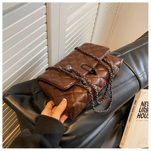 Detailed view of brown quilted crossbody bag with metal chain strap and leather textures