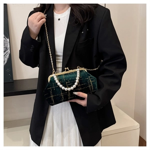 Détail du sac en velours vert avec poignée en perles et bandoulière dorée