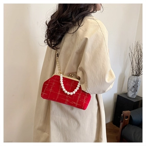 Sac en velours rouge matelassé avec poignée perle et chaîne dorée porté à l'épaule