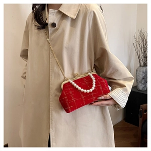 Détail d'un sac coquille en velours rouge avec anse perle et chaîne dorée sur mannequin