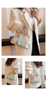 Detail of embroidered mint shell bag with metal handle, pearl strap and blue tassel