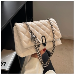 Macro detail of white quilted leather bag featuring classic diamond pattern and dark metal chain