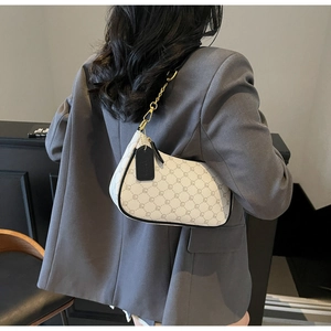 Close-up of retro monogram crescent bag with golden chain strap on model's shoulder