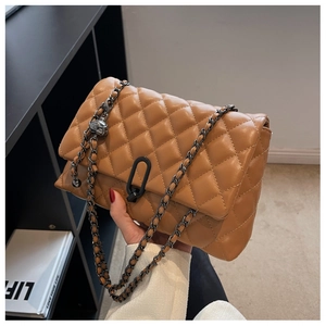 Detail of a brown quilted leather crossbody bag with chain strap and modern metal buckle
