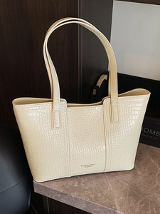 Sac fourre-tout beige à motif crocodile avec double sangle sur surface en pierre