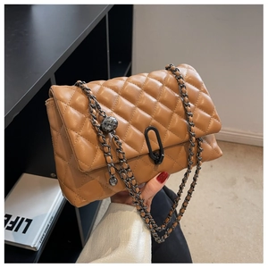 Detail of caramel brown quilted faux leather bag with metal lock and chain strap