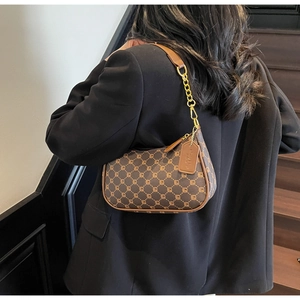 Detail of vintage brown monogram shoulder bag with gold chain strap on a model