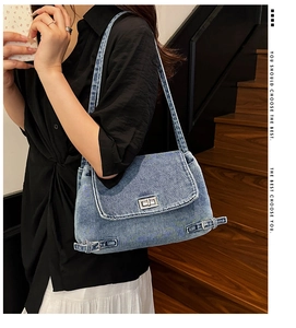 Détail du sac cabas en denim bleu avec fermoir rotatif argenté et texture rétro sur la bandoulière
