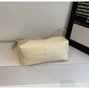 Détail de la couture en croix sur cuir litchi blanc crème d'un sac cabas minimaliste