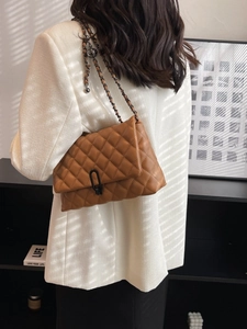 Brown quilted leather chain bag with black U-shaped lock shown on a female model