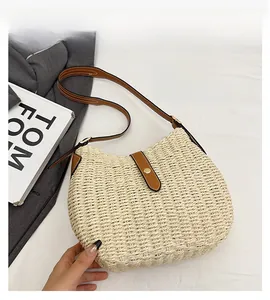 Gros plan sur un sac en paille tressée beige avec bandoulière en similicuir marron