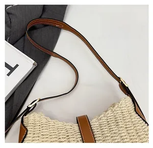Détail de la bandoulière en cuir marron réglable et de la texture tressée du sac paille