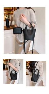Detail of black lychee grain leather bucket bag with top handles and mini zip pouch