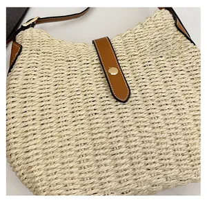 Détail d'un sac en paille tissée avec bandoulière en cuir marron et boucle dorée