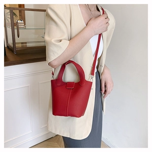Detail of red lychee grain leather bucket bag with top handle and fine shoulder strap