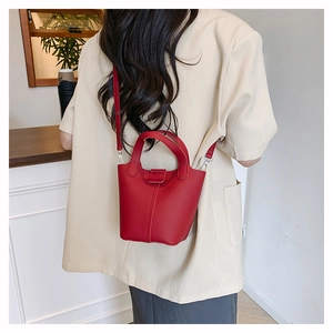 Detailed view of red pebble leather bucket bag shown on a person for scale