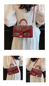 Detail of red Chinese style embroidery handbag with braided handle and gold buckle