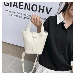 Detail of white litchi pattern leather bucket bag held by hand in minimalist urban style